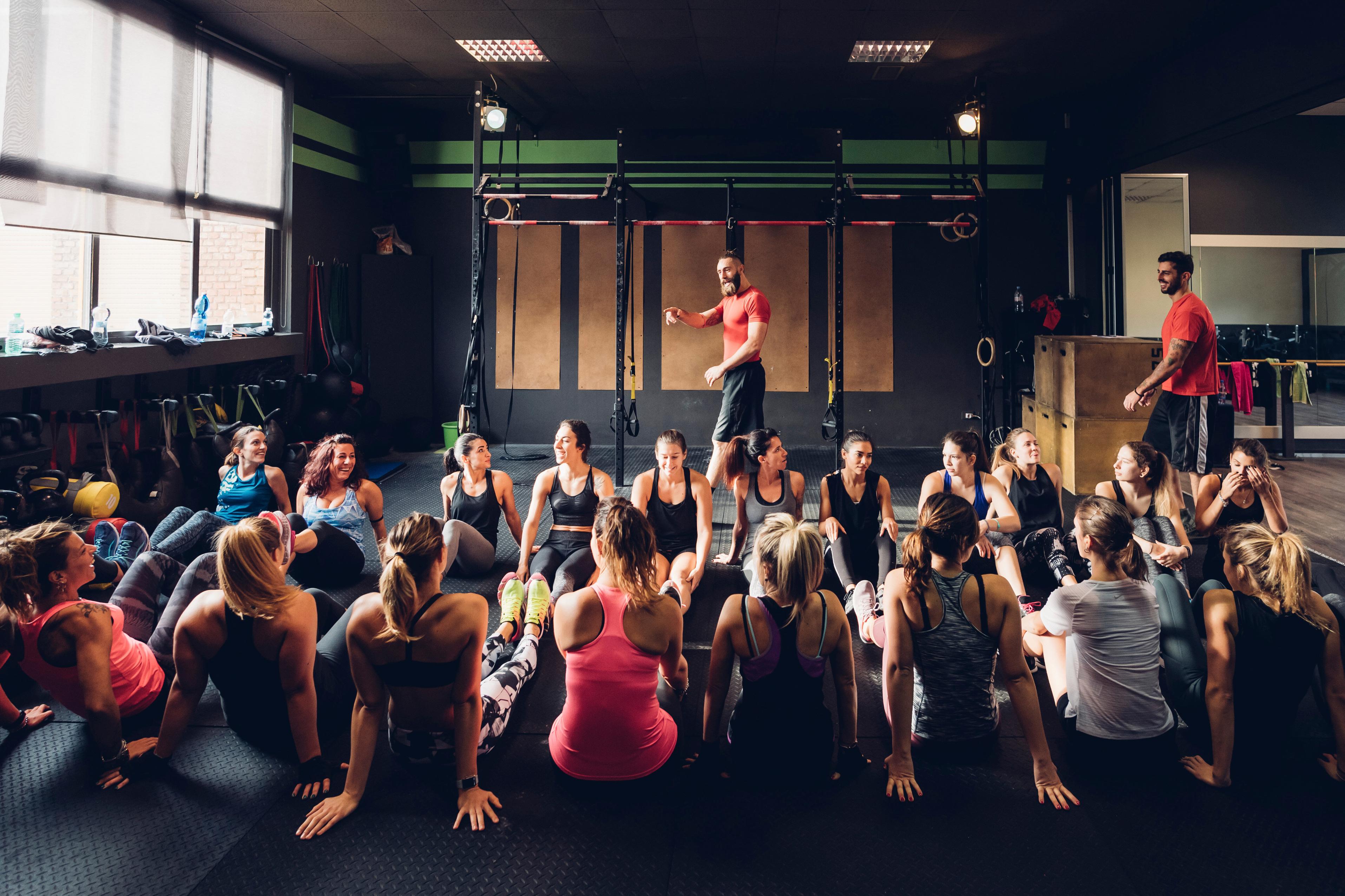 A large group seated in a gym listening to a seminar instructor