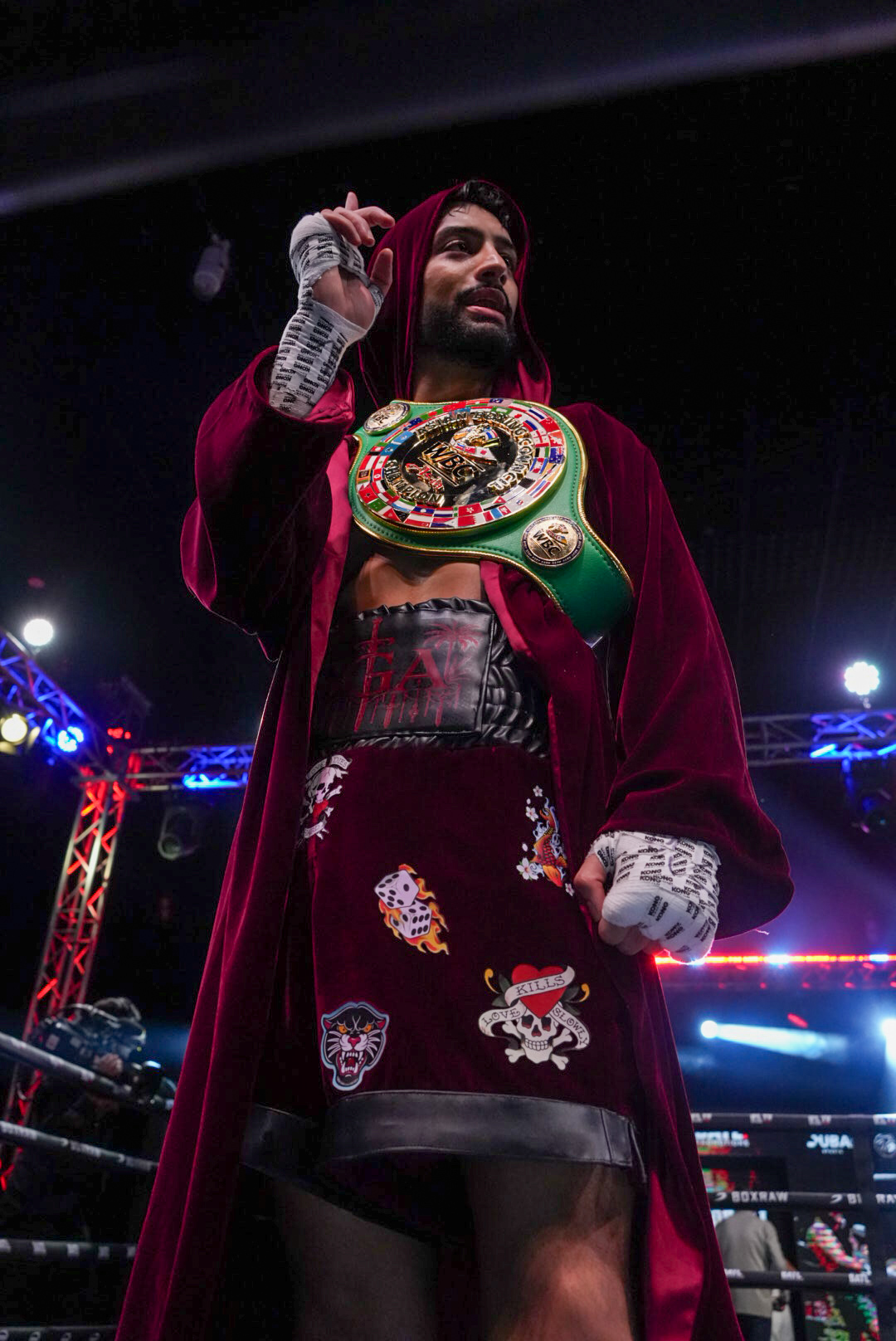 Victorious boxer raising both arms wearing a championship belt