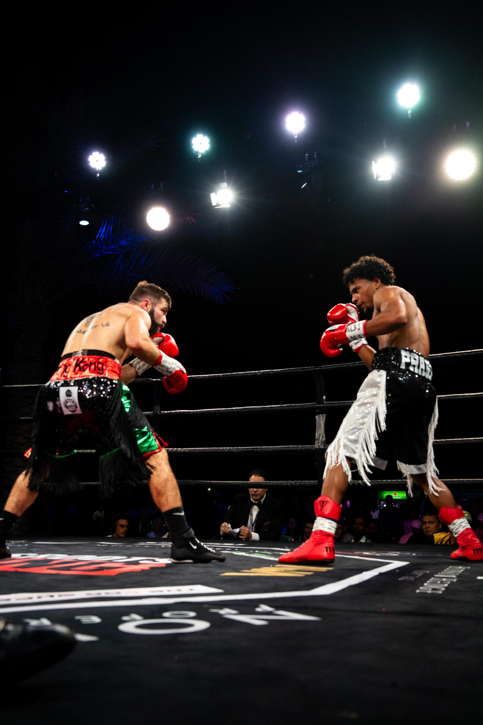 Two professional boxers exchanging punches under arena lights